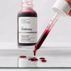 The Ordinary AHA BHA Peeling Solution red liquid droplets on glass surface