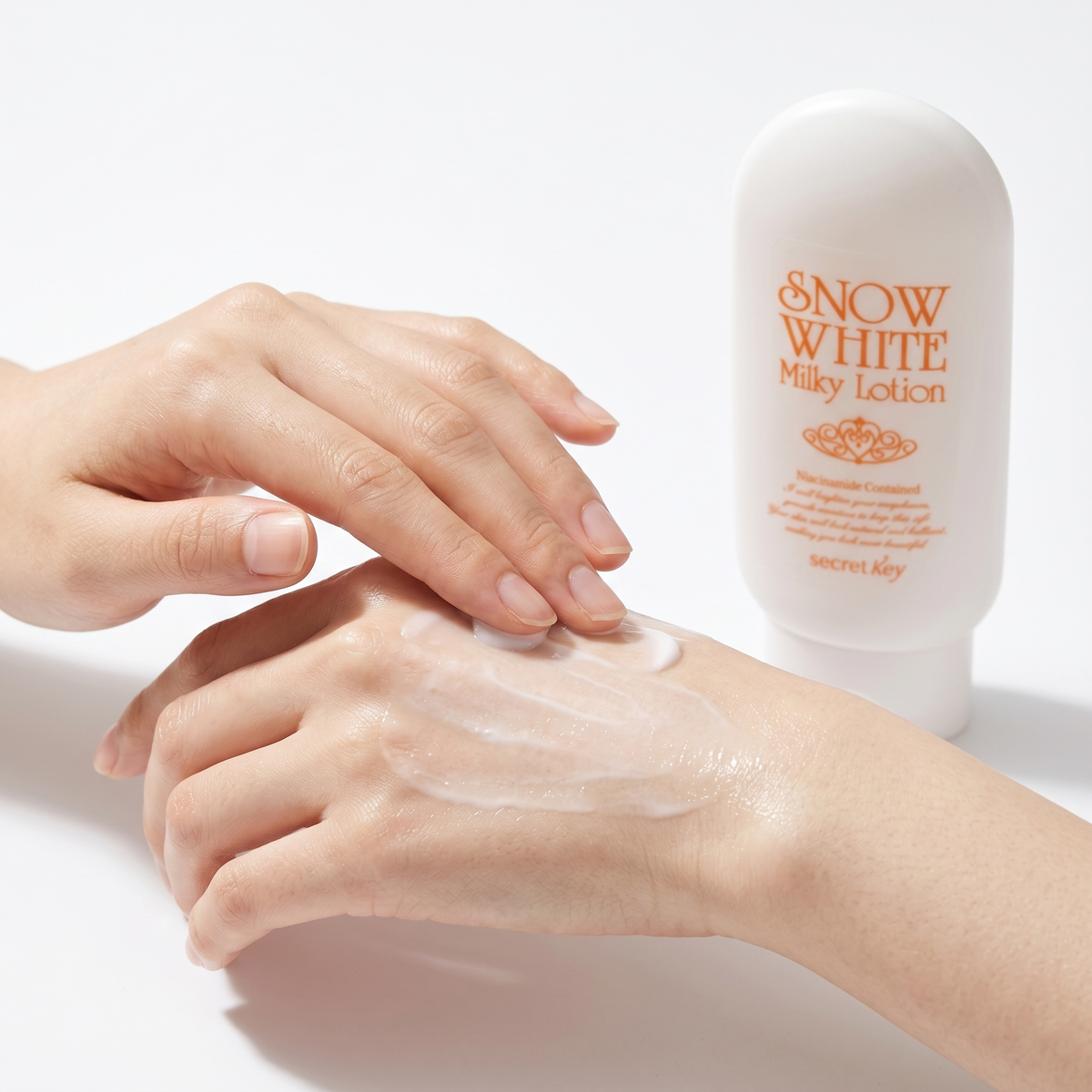 Applying Secret Key Snow White Milky Lotion on back of hand - creamy white tone-up texture